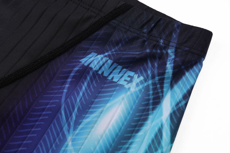 Close-up of 黑色男童泳褲 <68331022> with blue geometric feather-like pattern and white MNWEX text on the fabric.