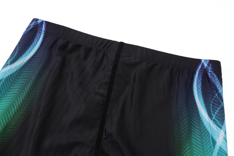 A close-up of the waistband and upper section of 黑色男童泳褲 <68331022> highlights blue and green feather-like side patterns, a central vertical seam, and stylish design details.
