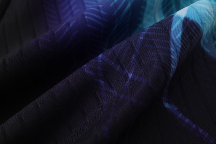 Close-up of dark fabric with a blue and purple leaf pattern and subtle vertical ribbing, showcasing the texture and folds of 黑色男童泳褲 <68331022>, perfect for stylish kids’ swimwear.