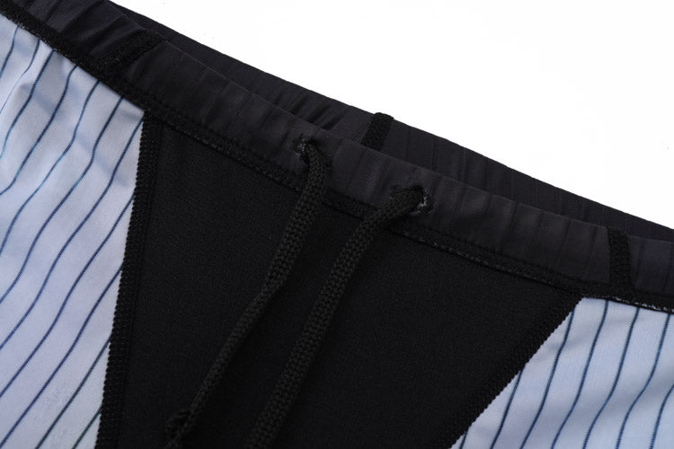 Close-up of the waistband and drawstring of 黑色男童泳褲 <68331022>, showing black fabric with white side panels featuring vertical blue pinstripes.