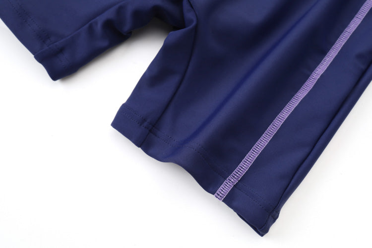 Close-up of the hem of a 深藍色女童練習泳衣 <68401830-H1>, showing a light purple stitched seam. The 彈性泳衣 fabric is smooth and stretchy, perfect for school or swim activities.