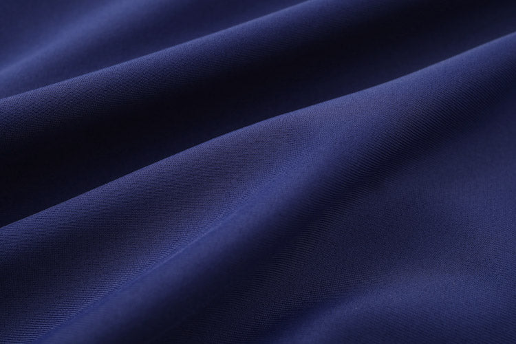 Close-up of 深藍色女童練習泳衣 <68401830-H1> fabric in dark blue, featuring gentle folds and a soft, smooth texture that creates wave-like patterns and subtle shadows across the surface.